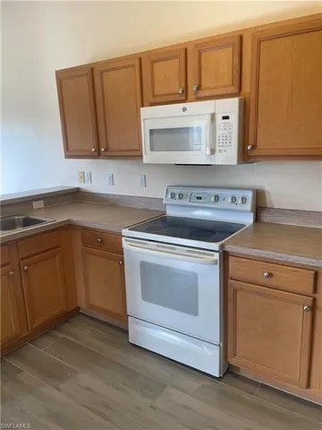 a kitchen with stainless steel appliances granite countertop a sink a stove and microwave with wooden floor