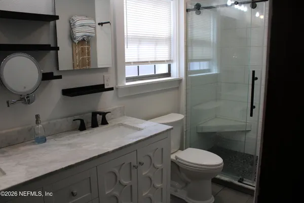 a bathroom with a granite countertop toilet sink and mirror