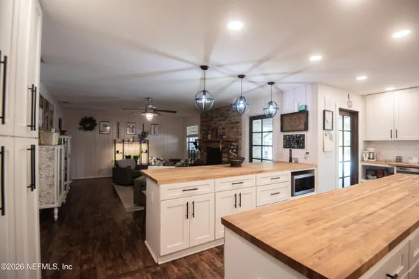 a kitchen with stainless steel appliances kitchen island granite countertop a refrigerator oven a sink dishwasher and white cabinets with wooden floor