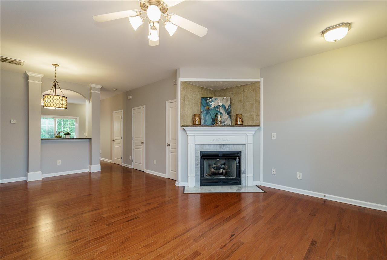 7675 Winners Edge Street Raleigh, NC 27617 - Photo 3 of 23 an empty room with wooden floor a fireplace and a chandelier
