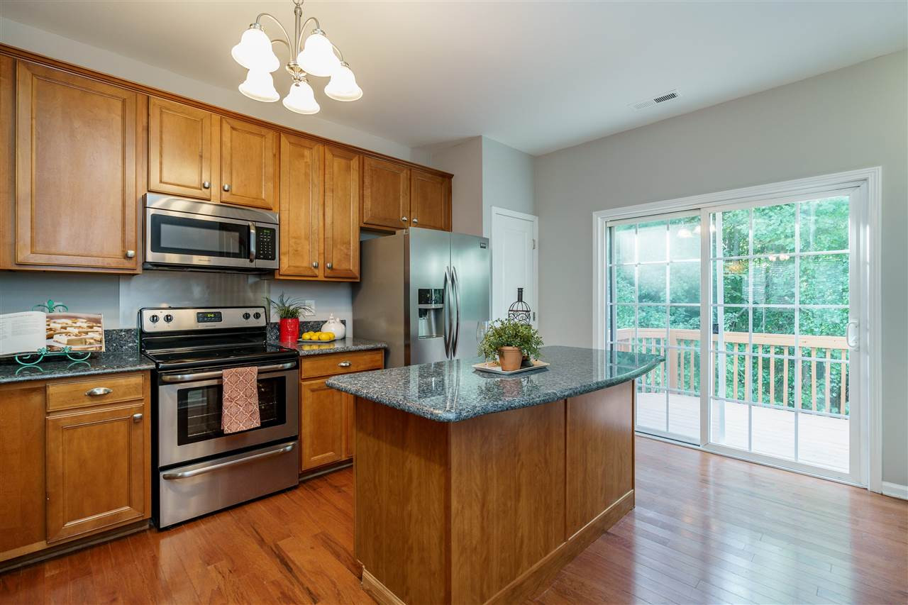 7675 Winners Edge Street Raleigh, NC 27617 - Photo 7 of 23 a kitchen with stainless steel appliances granite countertop a stove a refrigerator a sink dishwasher and wooden cabinets with wooden floor