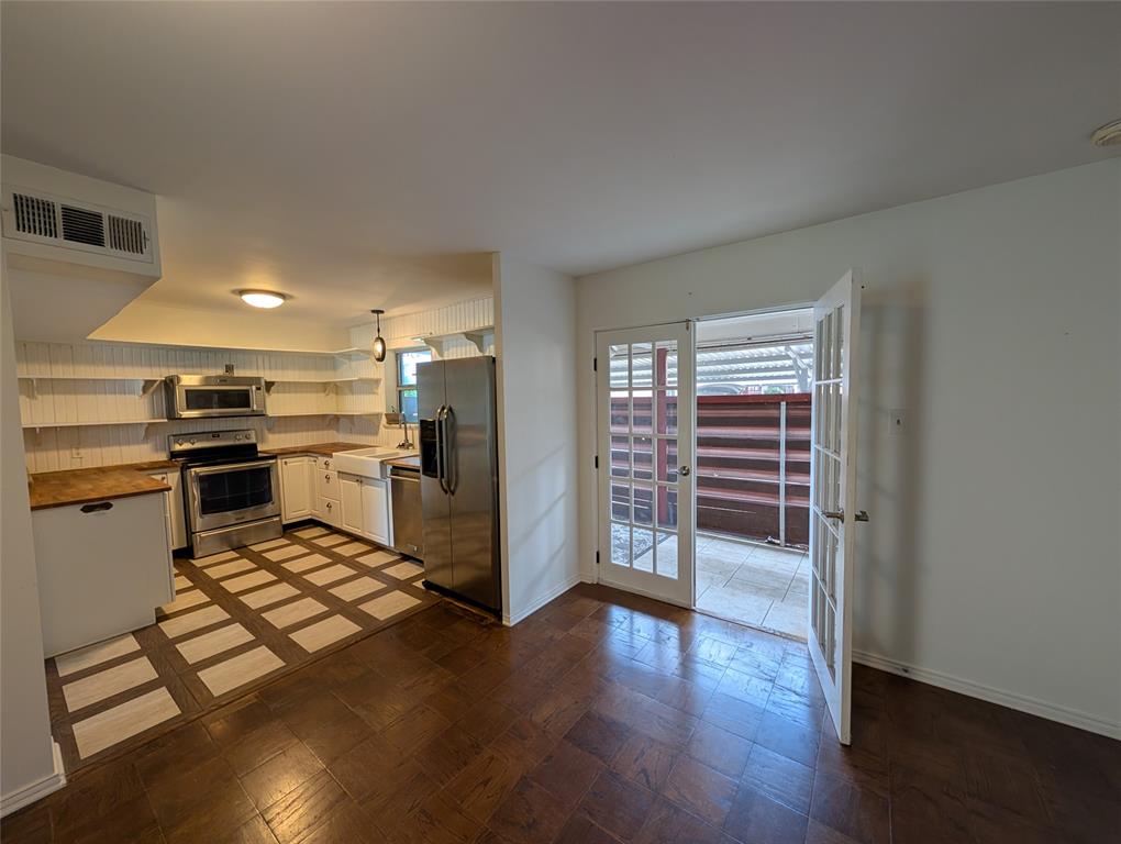 4715 Skillman Street, Unit A Dallas, TX 75206 - Photo 12 of 28 Modern kitchen featuring white cabinetry, stainless steel appliances, wood-finish countertops, and an apron-front sink