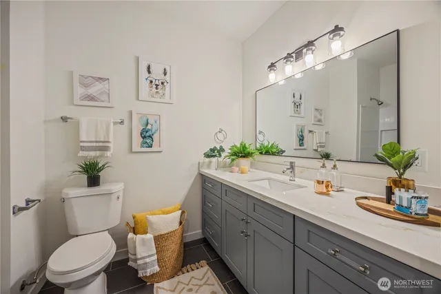 a bathroom with a granite countertop toilet sink and mirror