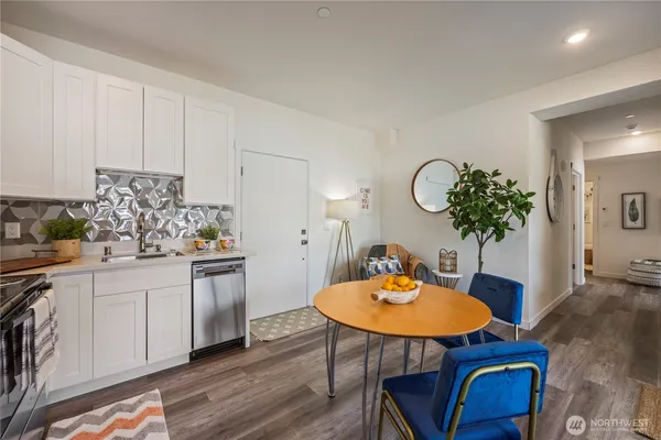 a kitchen with stainless steel appliances granite countertop a white table chairs and white cabinets