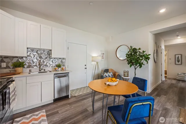 a kitchen with stainless steel appliances granite countertop a white table chairs and white cabinets
