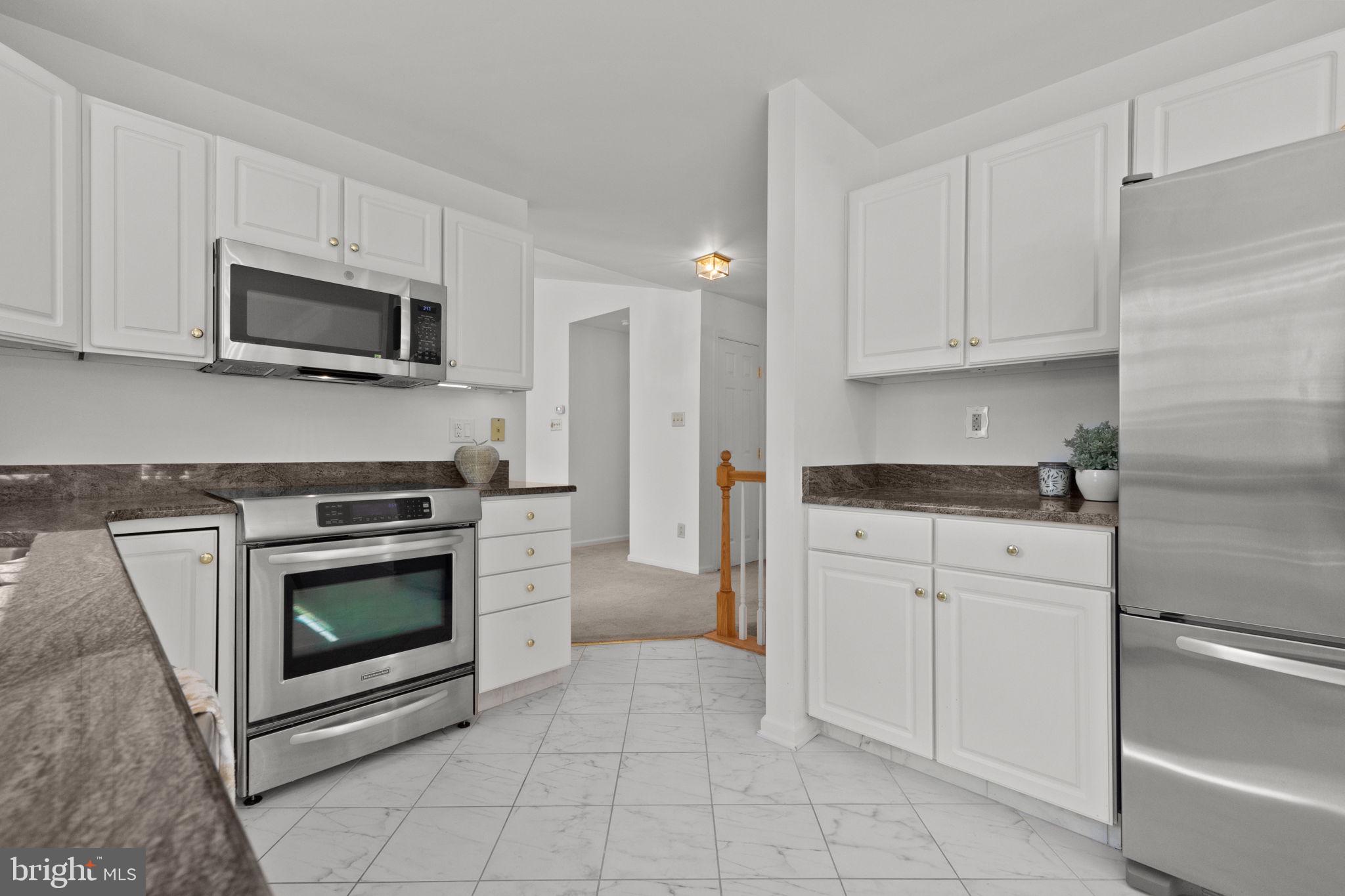 1102 Waterford Road, Unit 1 Yardley, PA 19067 - Photo 4 of 31 a kitchen with granite countertop white cabinets and stainless steel appliances