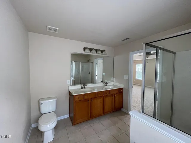 a spacious bathroom with a granite countertop toilet a sink and a mirror