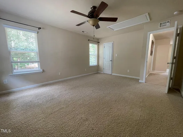 an empty room with windows and chandelier fan