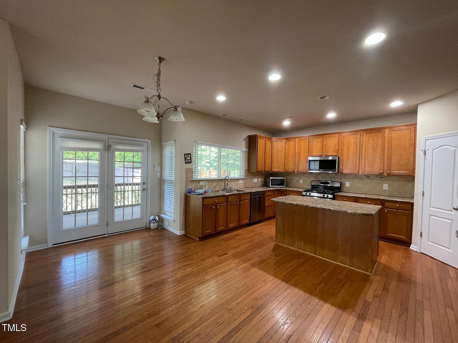 2107 Toad Hollow Trail Apex, NC 27502 - Photo 5 of 28 a large kitchen with stainless steel appliances granite countertop a refrigerator a sink dishwasher a stove and a large countertops with wooden floor