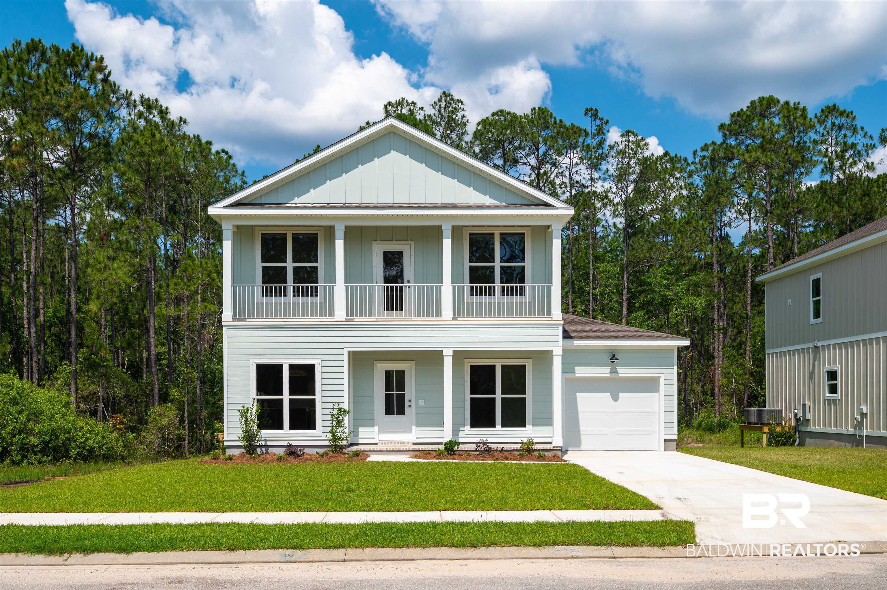657 Island Way Gulf Shores, AL 36542 - Photo 1 of 59 View of front facade featuring a balcony, an attached garage, driveway, covered porch, and a front yard