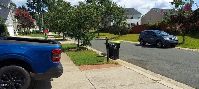 a front view of a house with a garden and trees