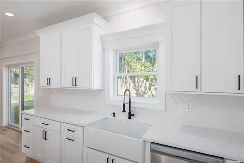 a kitchen with white cabinets and a window