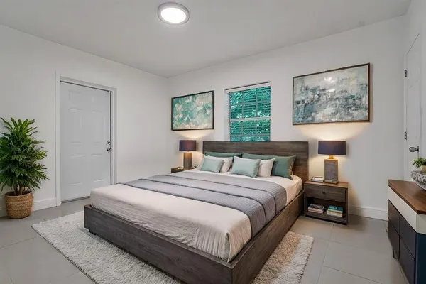 a bedroom with a large bed and a potted plant