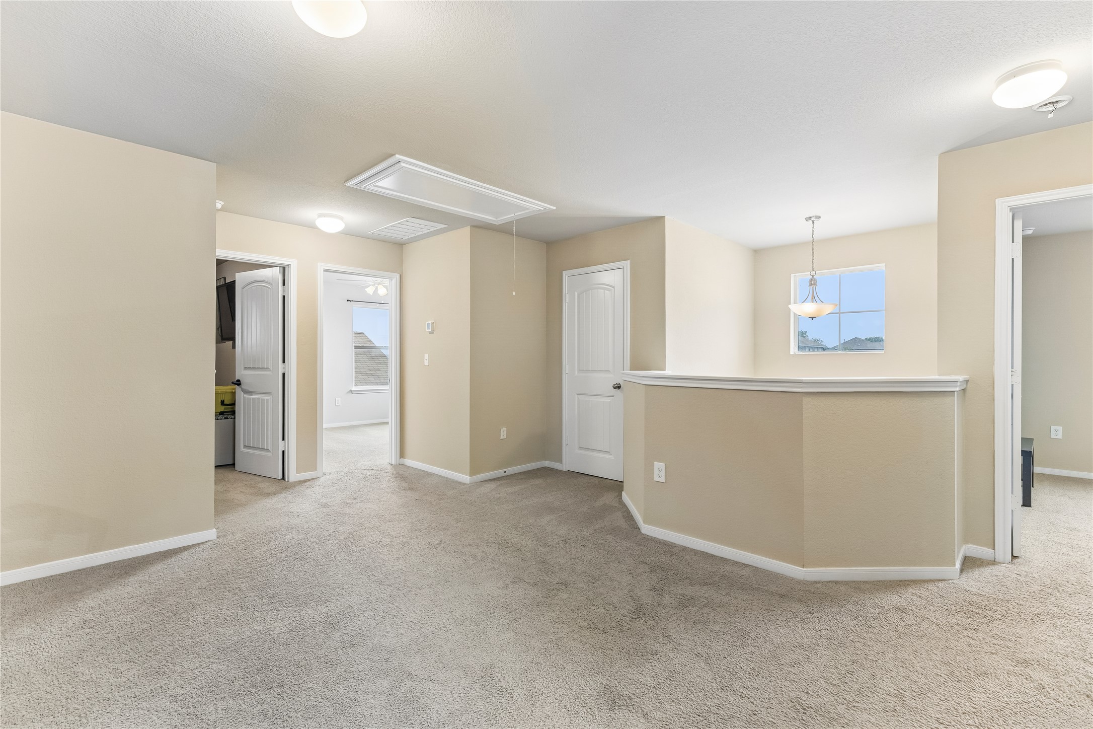 14409 Estuary Road Manor, TX 78653 - Photo 20 of 24 Carpeted loft area featuring a partial wall, a window with an overhead light fixture, and multiple doorways