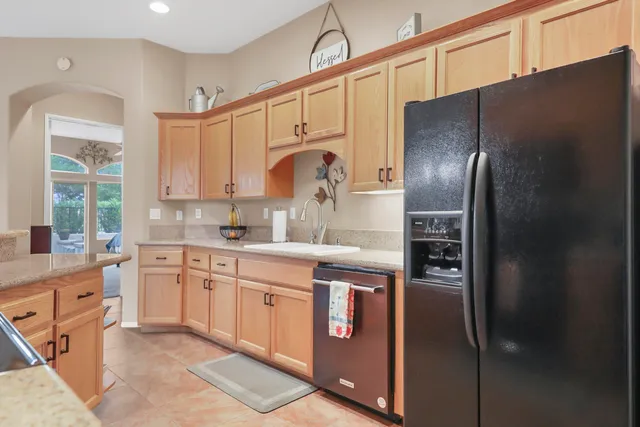 a kitchen with stainless steel appliances granite countertop a refrigerator a sink and white cabinets