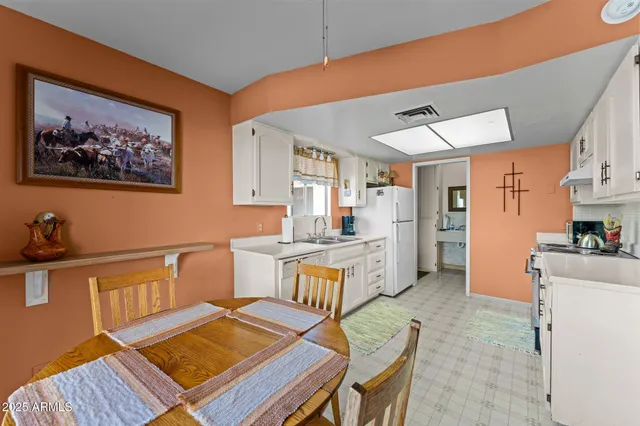a kitchen with a table chairs refrigerator and a sink