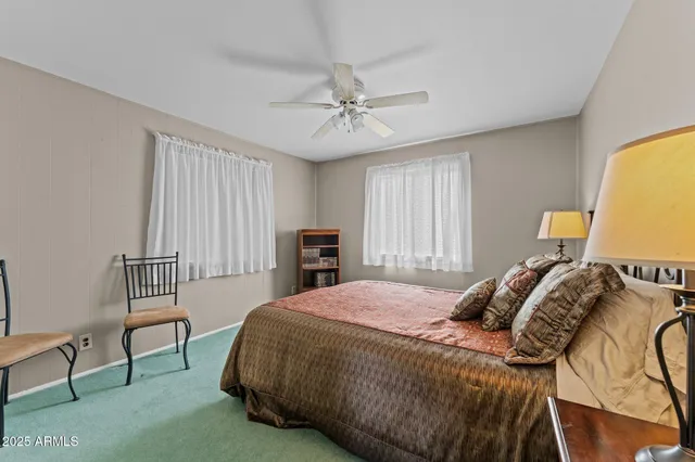 a bedroom with a bed a chair and potted plant on the dresser