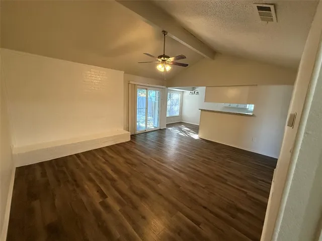 an empty room with wooden floor ceiling fan and windows