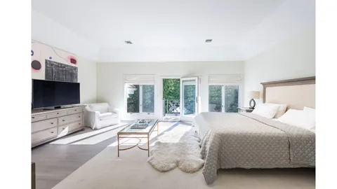 a bedroom with a bed and large windows
