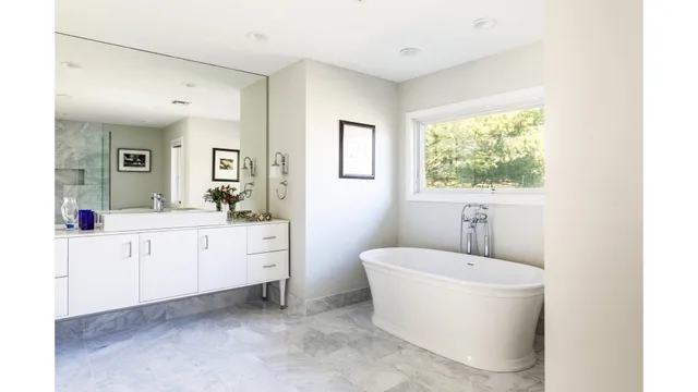 a bathroom with a white tub a sink a window and a mirror