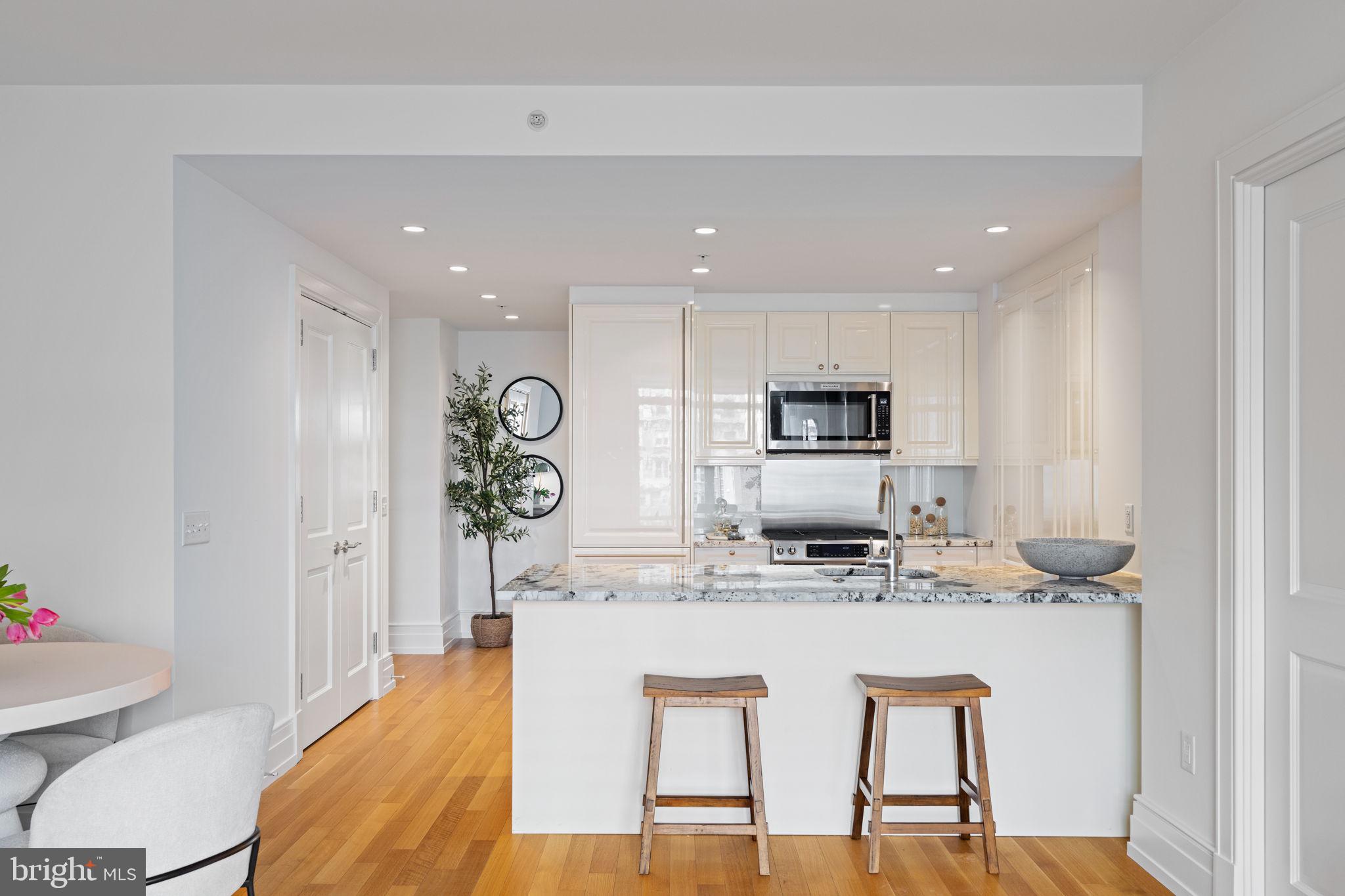 130 South 18th Street, Unit 501 Philadelphia, PA 19103 - Photo 11 of 43 a kitchen with stainless steel appliances granite countertop a sink a stove a microwave a refrigerator a kitchen island and chairs