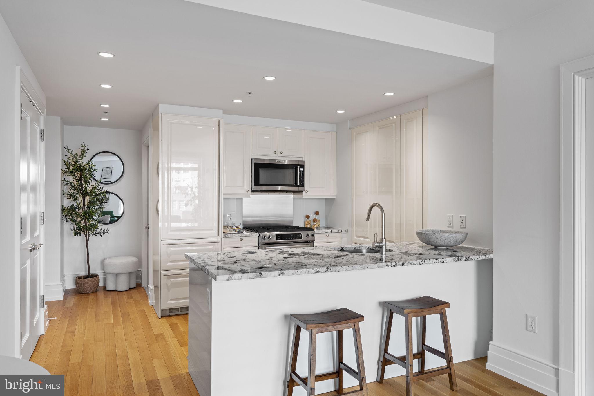 130 South 18th Street, Unit 501 Philadelphia, PA 19103 - Photo 9 of 43 a kitchen with stainless steel appliances granite countertop a stove top oven a sink a refrigerator white cabinets and wooden floor