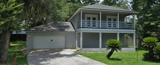 a front view of a house with a yard and potted plants