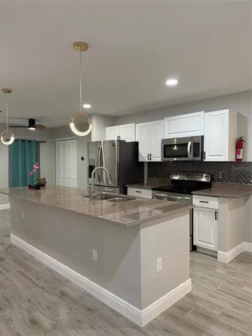 a kitchen with stainless steel appliances granite countertop a sink a stove a refrigerator and a oven with wooden floor