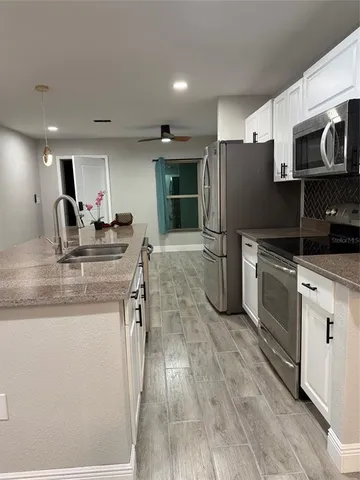 a kitchen with stainless steel appliances granite countertop a refrigerator oven a sink dishwasher and white cabinets with wooden floor