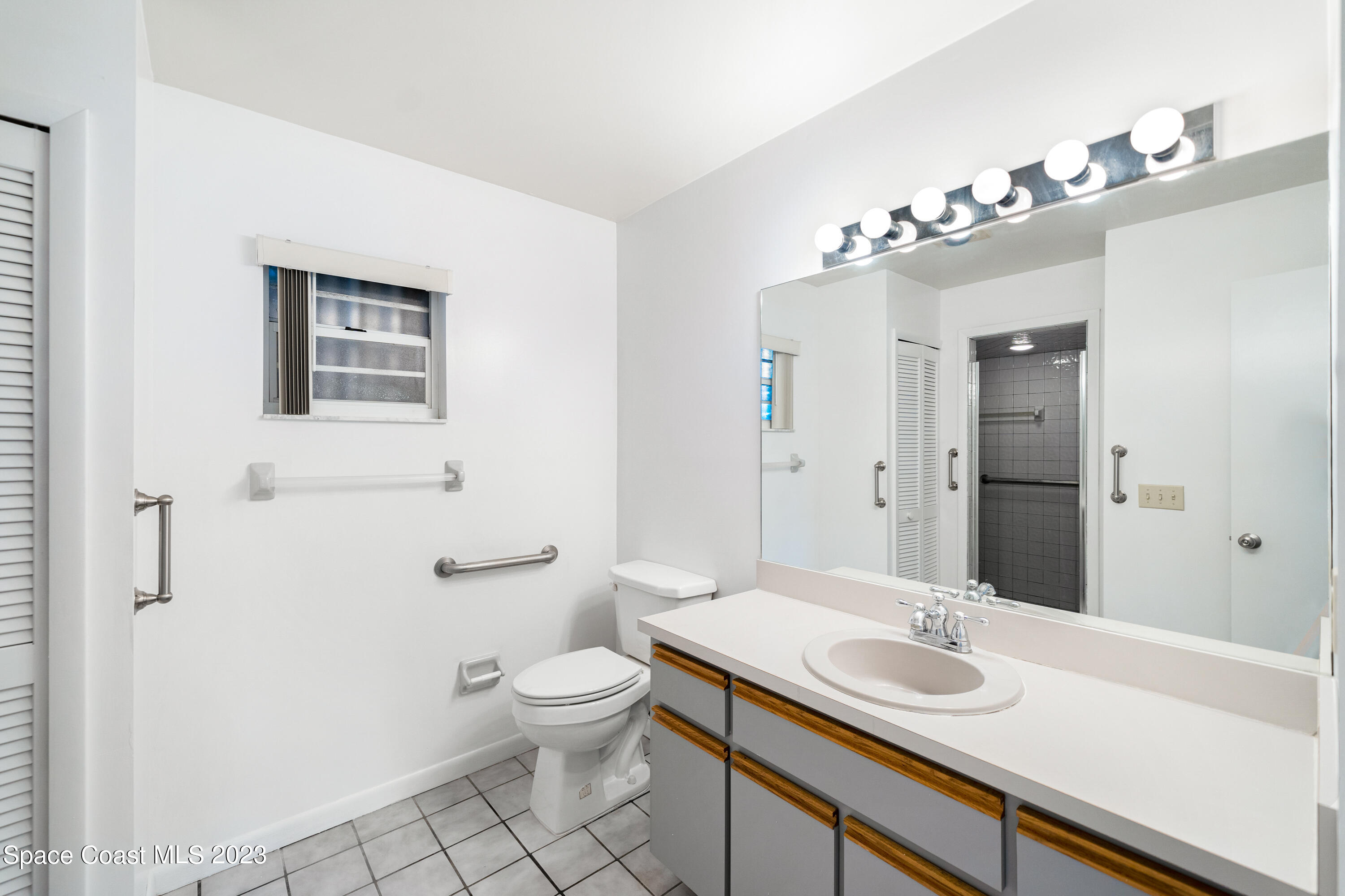7746 Mango Grove Avenue Melbourne, FL 32904 - Photo 11 of 21 a bathroom with a toilet a sink and mirror