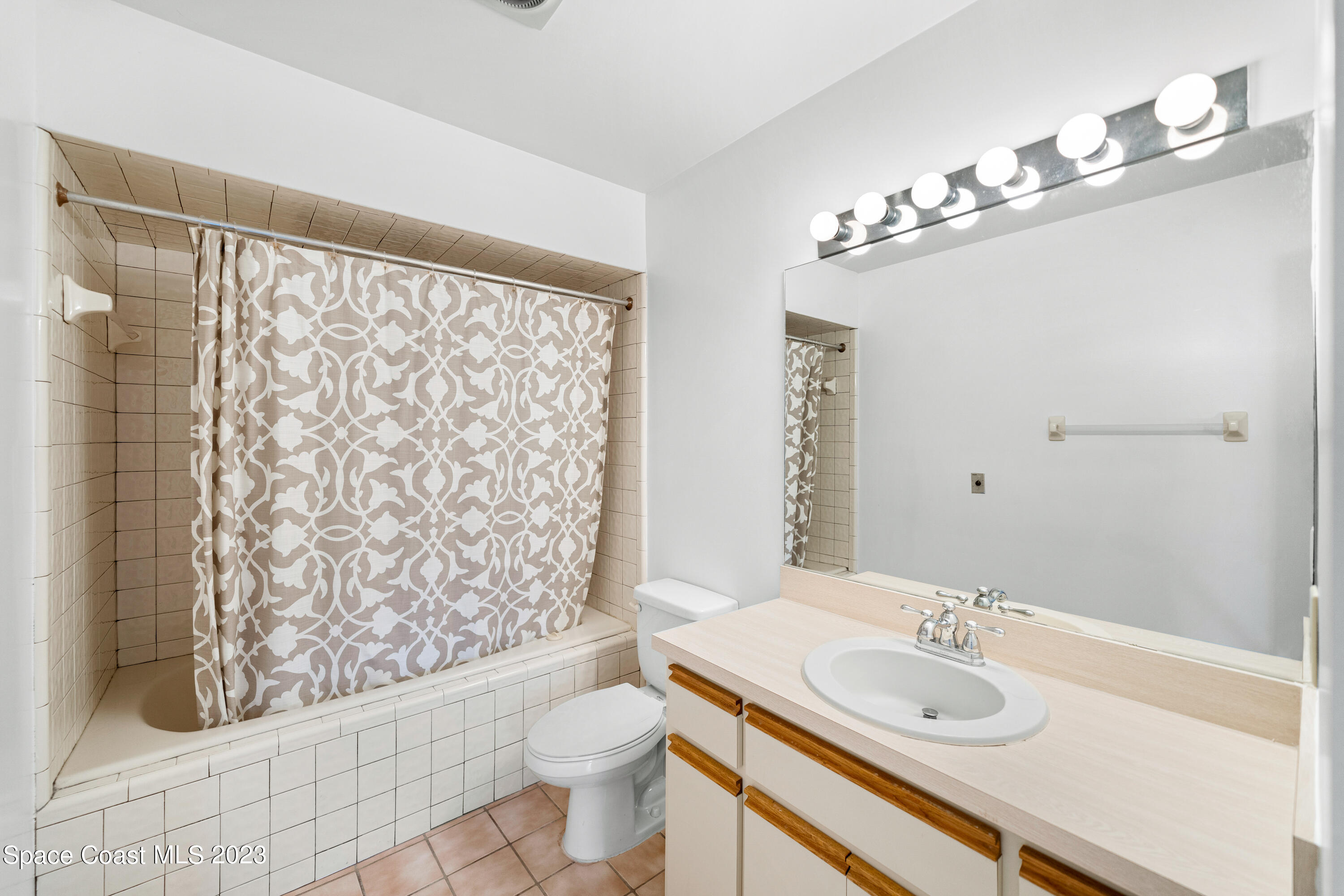 7746 Mango Grove Avenue Melbourne, FL 32904 - Photo 15 of 21 a bathroom with a sink a toilet a mirror and shower curtain