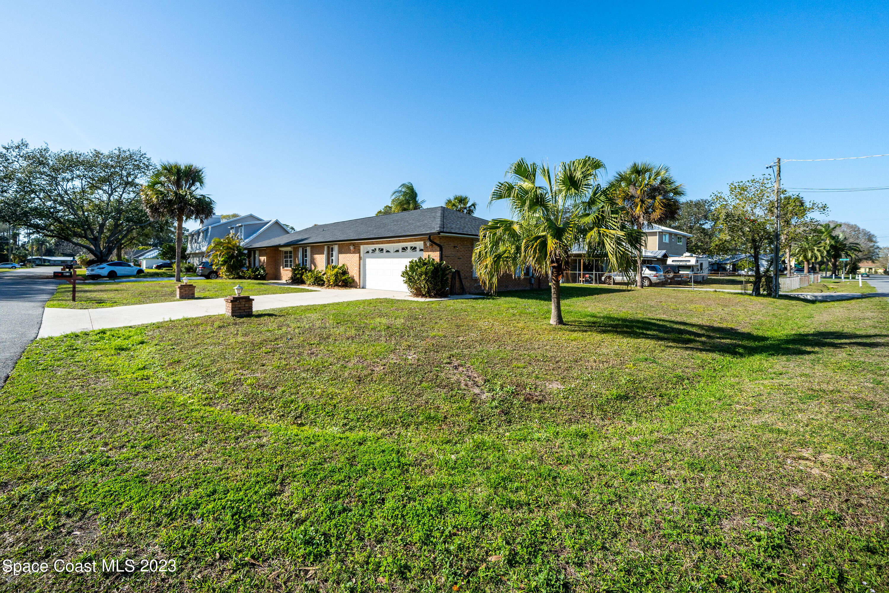 7746 Mango Grove Avenue Melbourne, FL 32904 - Photo 3 of 21 a view of a house with a big yard and palm trees