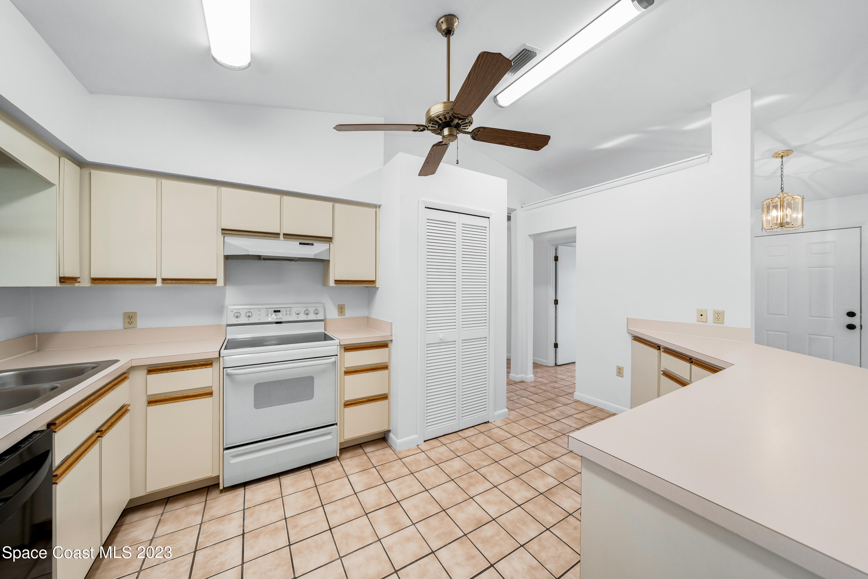 7746 Mango Grove Avenue Melbourne, FL 32904 - Photo 8 of 21 a kitchen with a stove a refrigerator and white cabinets