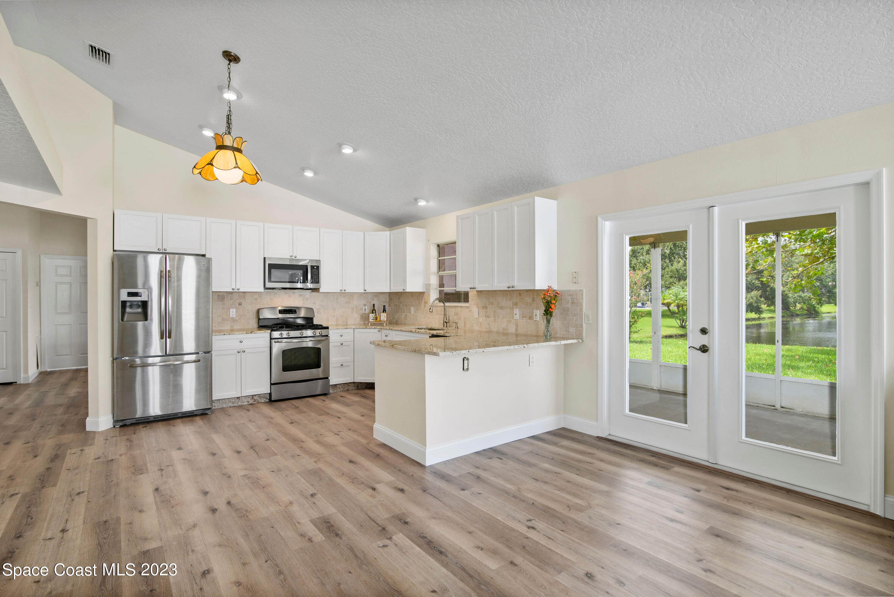 3360 Holly Springs Road Melbourne, FL 32934 - Photo 28 of 42 a kitchen with white cabinets and stainless steel appliances