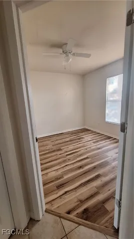 a view of empty room with wooden floor and fan