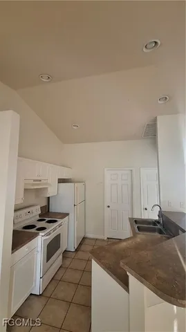 a kitchen with granite countertop a sink and white cabinets