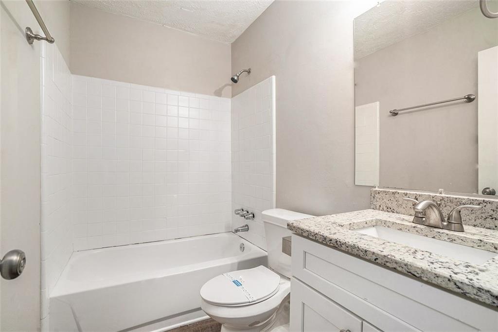4442 Cedar Ridge Trail Stone Mountain, GA 30083 - Photo 13 of 15 a bathroom with a granite countertop sink a toilet and a bathtub