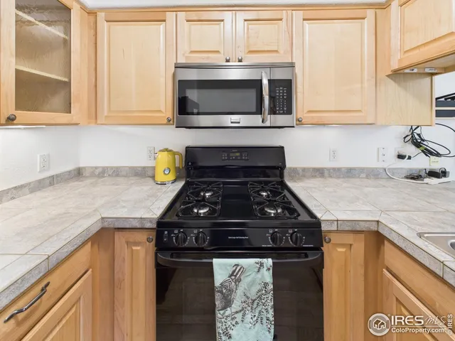 a kitchen with stainless steel appliances granite countertop a refrigerator a stove a sink and a microwave