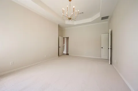 an empty room with a chandelier fan and windows