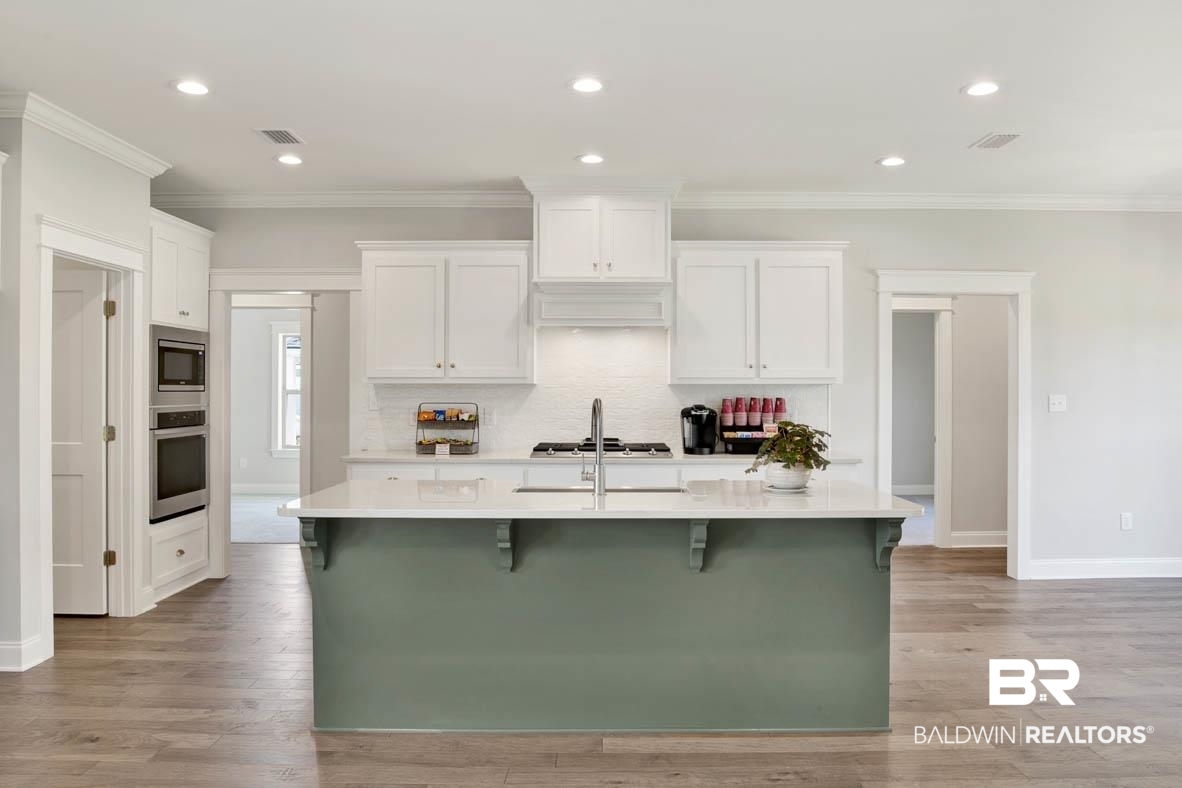 393 Garrison Boulevard Fairhope, AL 36532 - Photo 8 of 40 Kitchen with appliances with stainless steel finishes, white cabinetry, a kitchen island with sink, and a kitchen breakfast bar