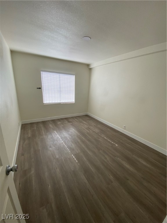 1711 Santa Paula Drive, Unit B Las Vegas, NV 89104 - Photo 9 of 17 Empty room with dark wood-type flooring and a textured ceiling