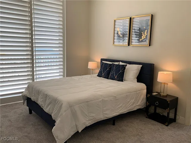 a bedroom with a bed and a lamp on dresser