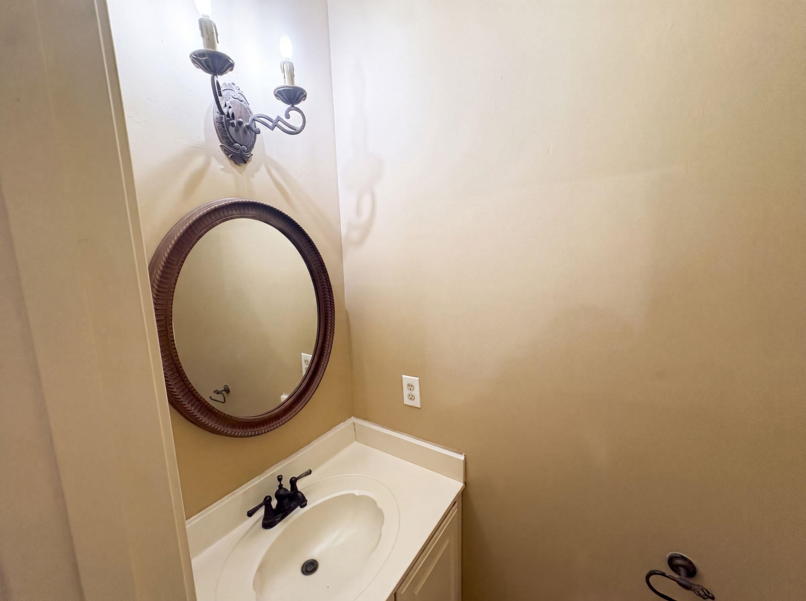 9424 Gotten Road Germantown, TN 38139 - Photo 20 of 27 Vanity area featuring a round mirror with a textured frame, white countertop, and a dark bronze faucet