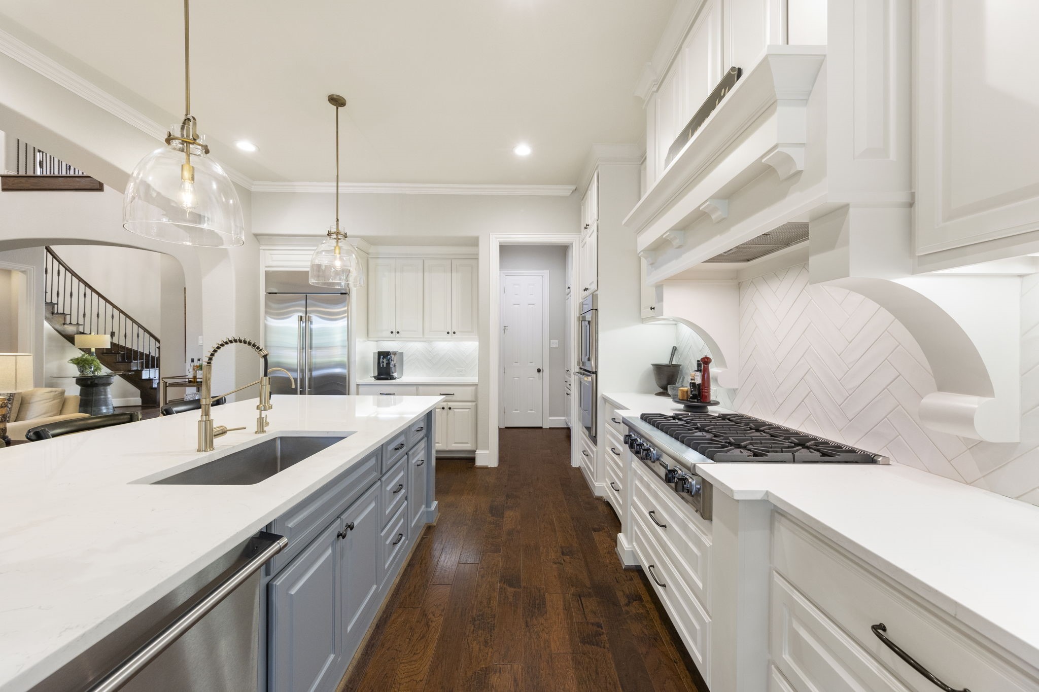 22 Marin Creek Place Spring, TX 77389 - Photo 12 of 38 Designer kitchen with quartz countertops, custom cabinetry, and a professional-grade gas cooktop framed by an elegant hood. Oversized island with statement pendant lighting creates a stunning focal point for entertaining.
