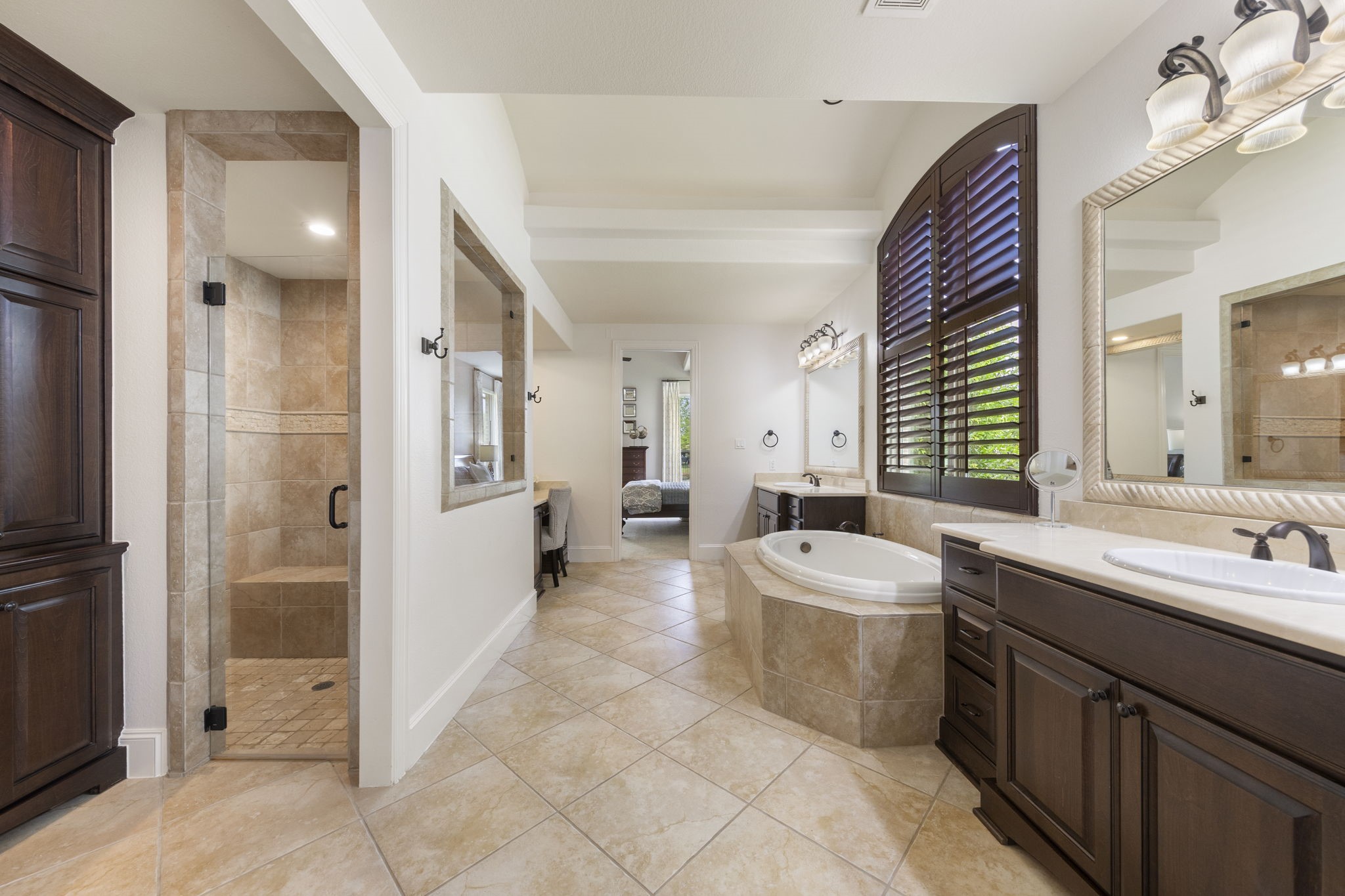 22 Marin Creek Place Spring, TX 77389 - Photo 17 of 38 Expansive primary bath retreat featuring an oversized walk-in shower, soaking tub framed by arched shutters, and elegant cabinetry with generous counter space.