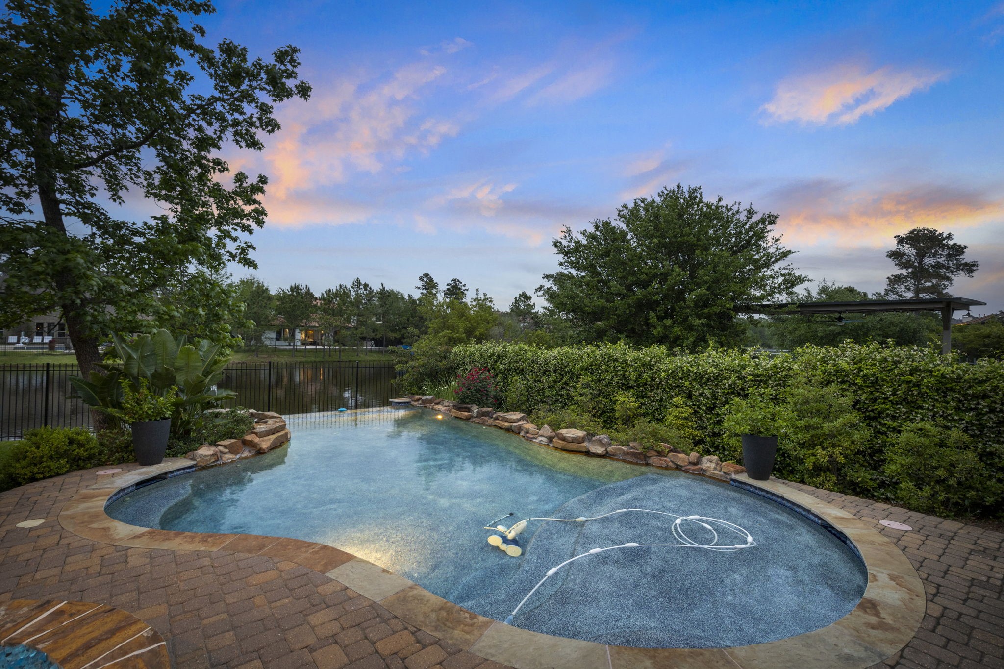 22 Marin Creek Place Spring, TX 77389 - Photo 34 of 38 Freeform pool with stone accents and serene views of Lake Paloma. Lush landscaping and peaceful water views create a beautiful backyard retreat.