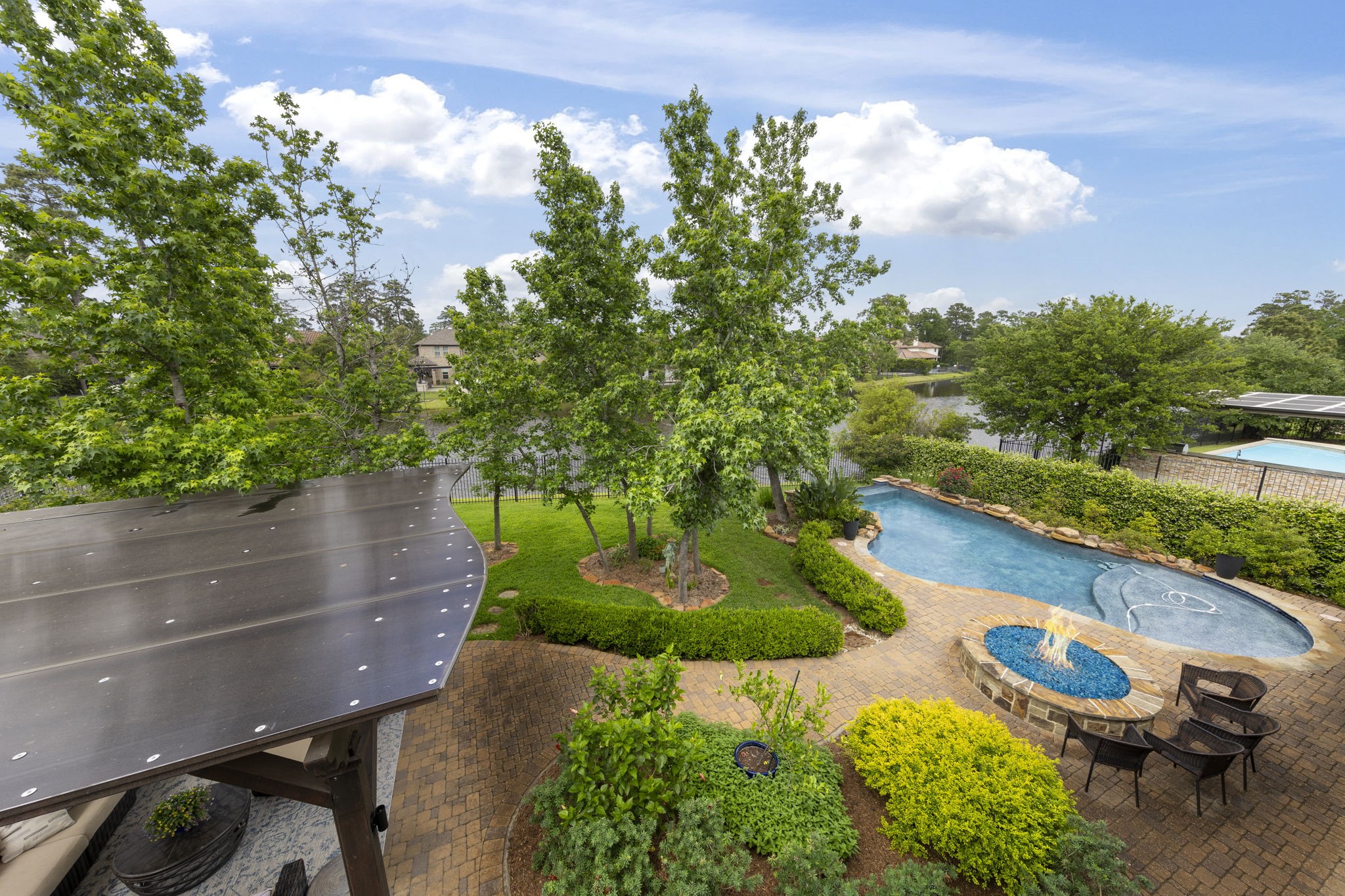 22 Marin Creek Place Spring, TX 77389 - Photo 35 of 38 Elevated balcony views overlooking the beautifully landscaped backyard, featuring a resort-style pool, fire feature, and mature trees, with tranquil water views creating a peaceful and private outdoor setting.