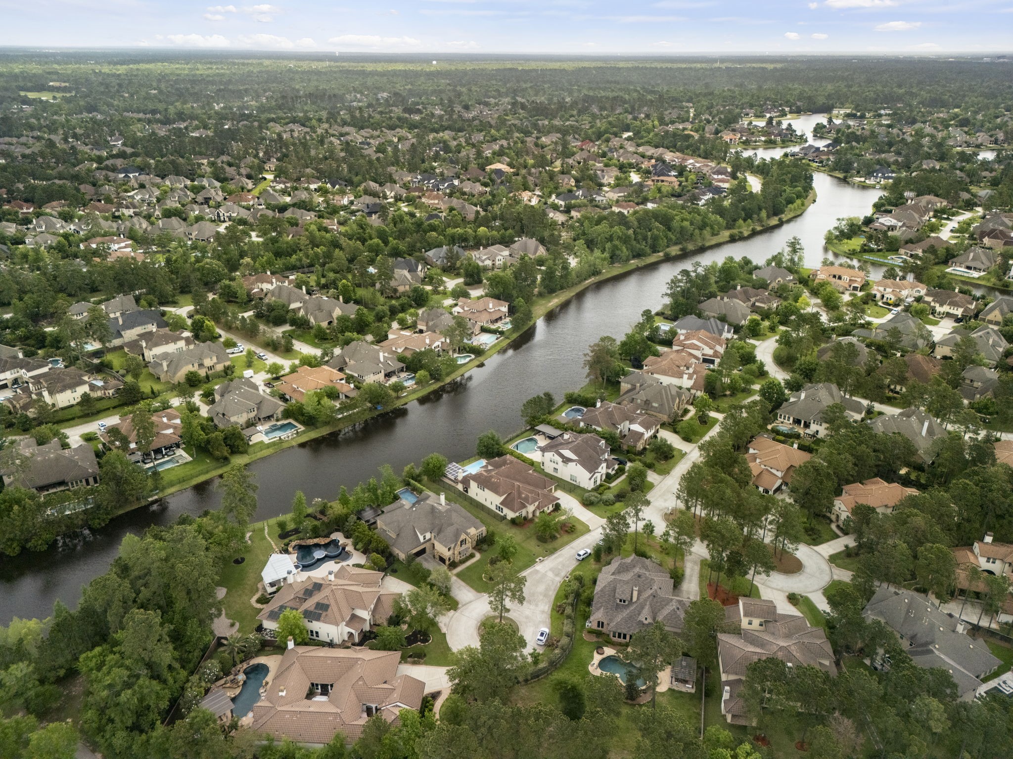 22 Marin Creek Place Spring, TX 77389 - Photo 38 of 38 Sweeping aerial perspective highlighting the scenic lake winding through the community, surrounded by beautifully maintained homes, mature trees, and peaceful waterfront living.