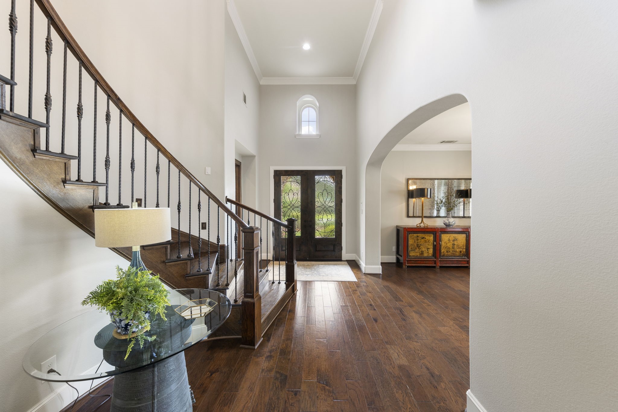 22 Marin Creek Place Spring, TX 77389 - Photo 5 of 38 Light-filled foyer with soaring ceilings, rich wood flooring, and a graceful staircase with iron balusters. Elegant architectural arches frame the inviting entry.