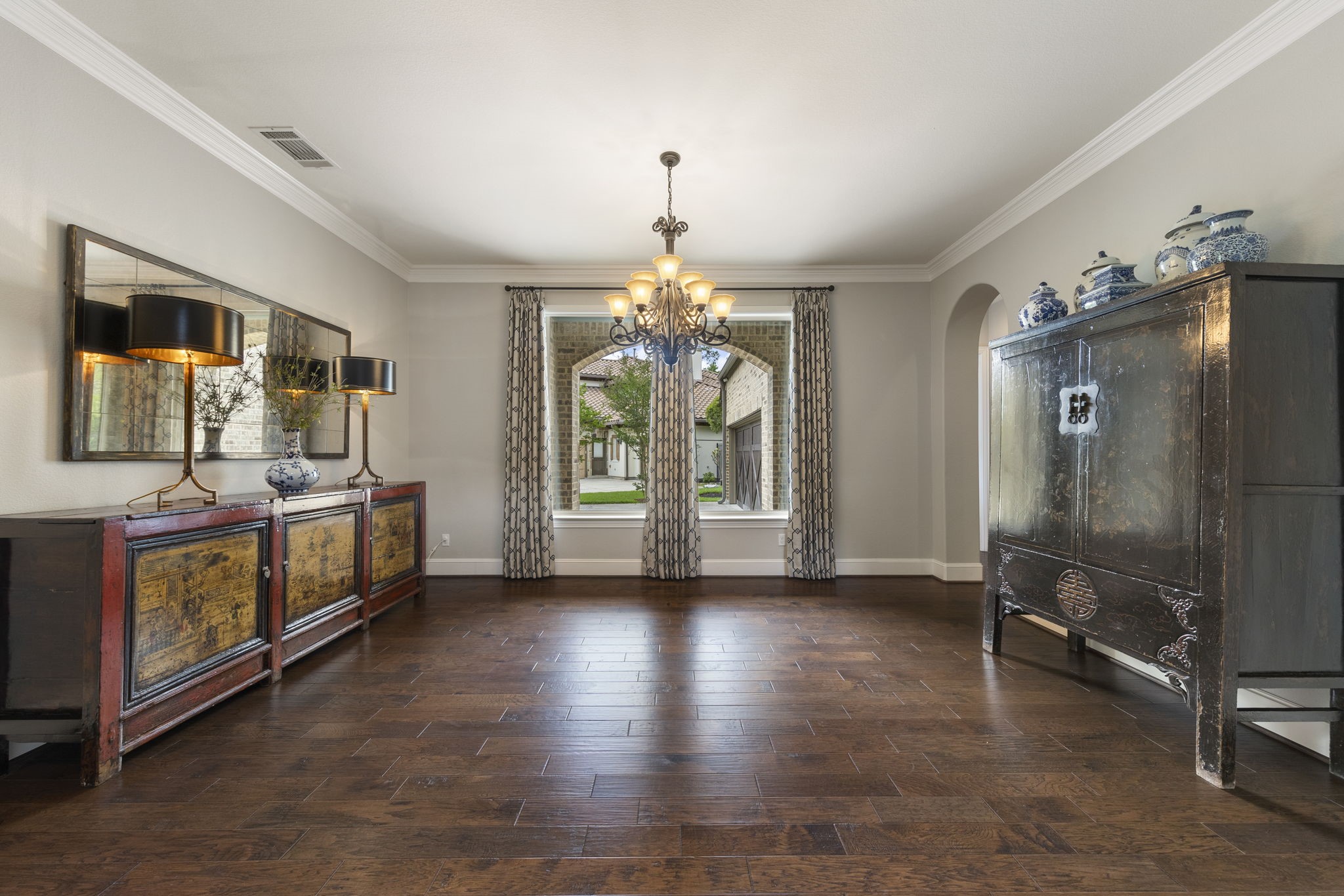 22 Marin Creek Place Spring, TX 77389 - Photo 6 of 38 Sophisticated formal dining room with rich wood flooring, detailed crown molding, and a dramatic chandelier that anchors the space. Expansive window invites natural light and frames picturesque courtyard views.
